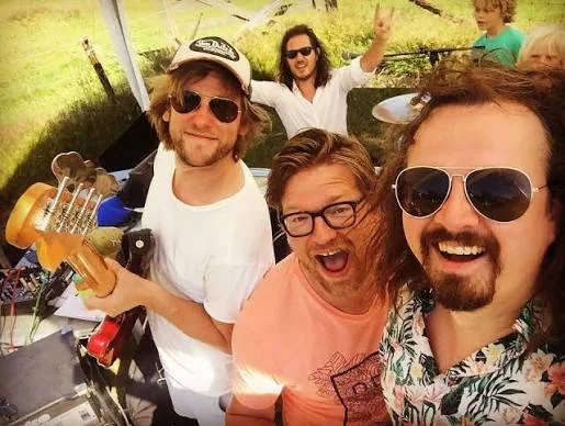 Milkbar maakt een selfie op het podium, met gitaar, zonnebrillen en publiek op de achtergrond